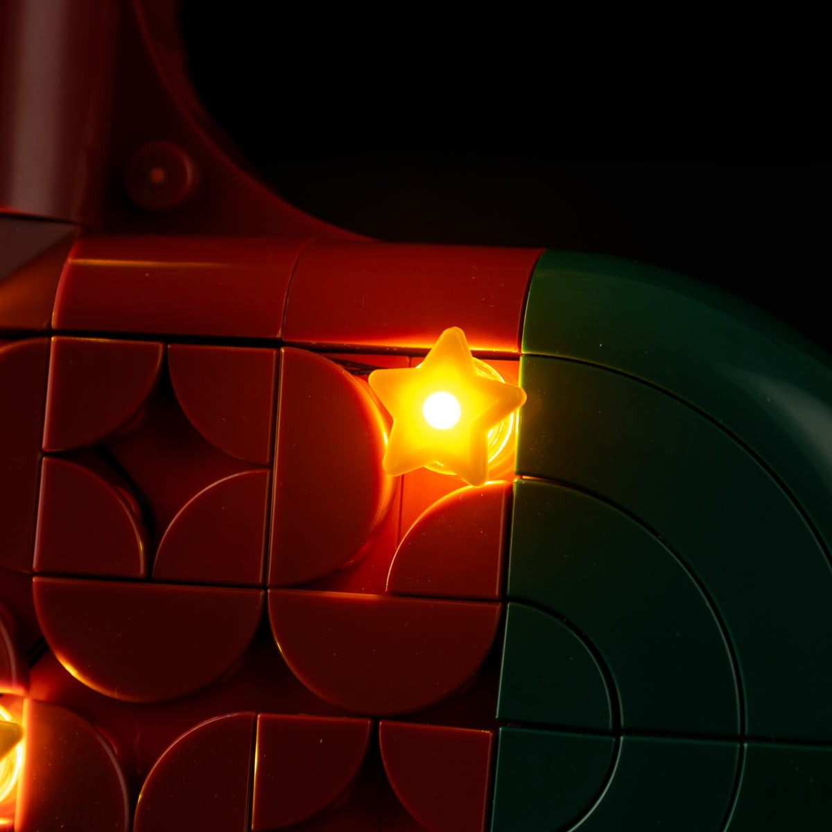 Real illuminated golden star beside the dark green toe of LEGO® Christmas Stocking 40958.
