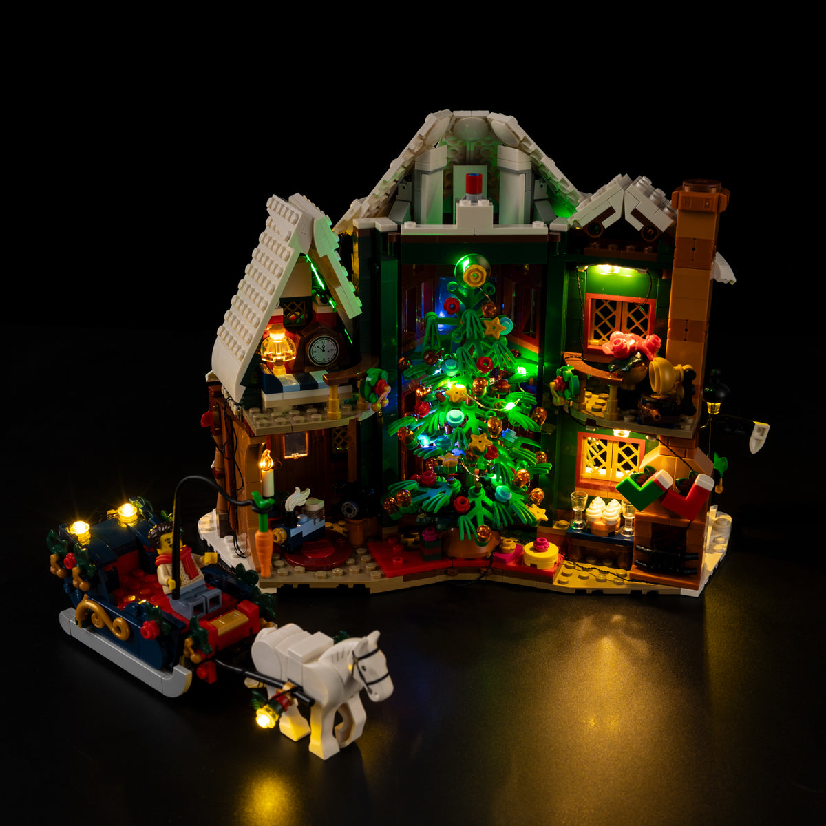 Open interior of LEGO® Holiday House 11387 with the Christmas tree and warm illuminated rooms.