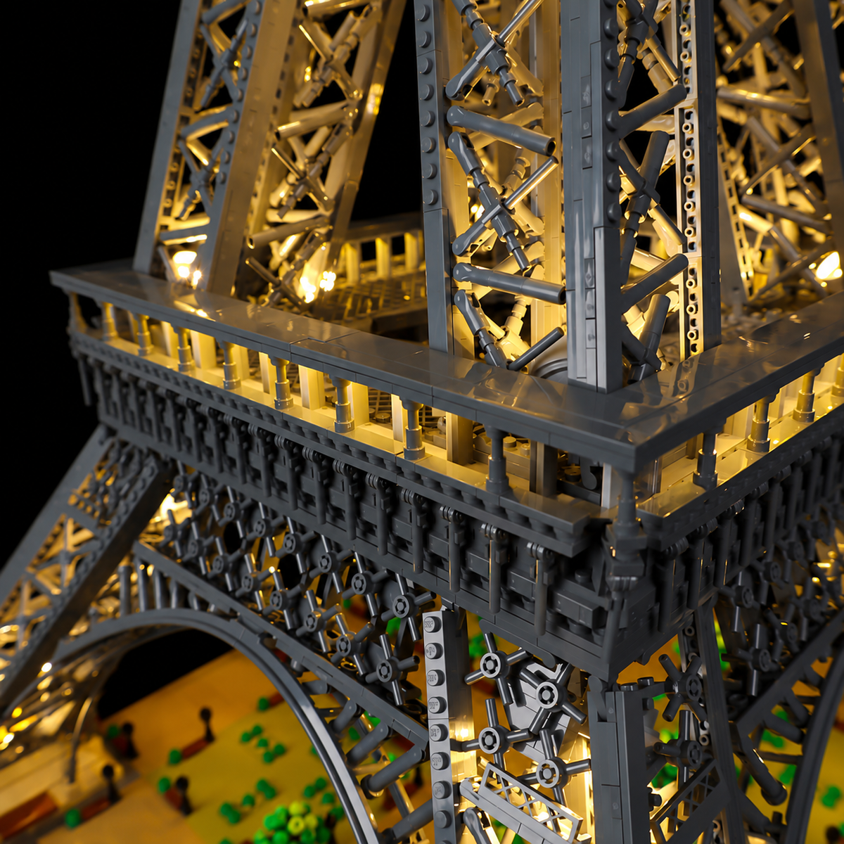 Real warm-white lighting beneath a LEGO Eiffel Tower observation platform and its lattice supports.