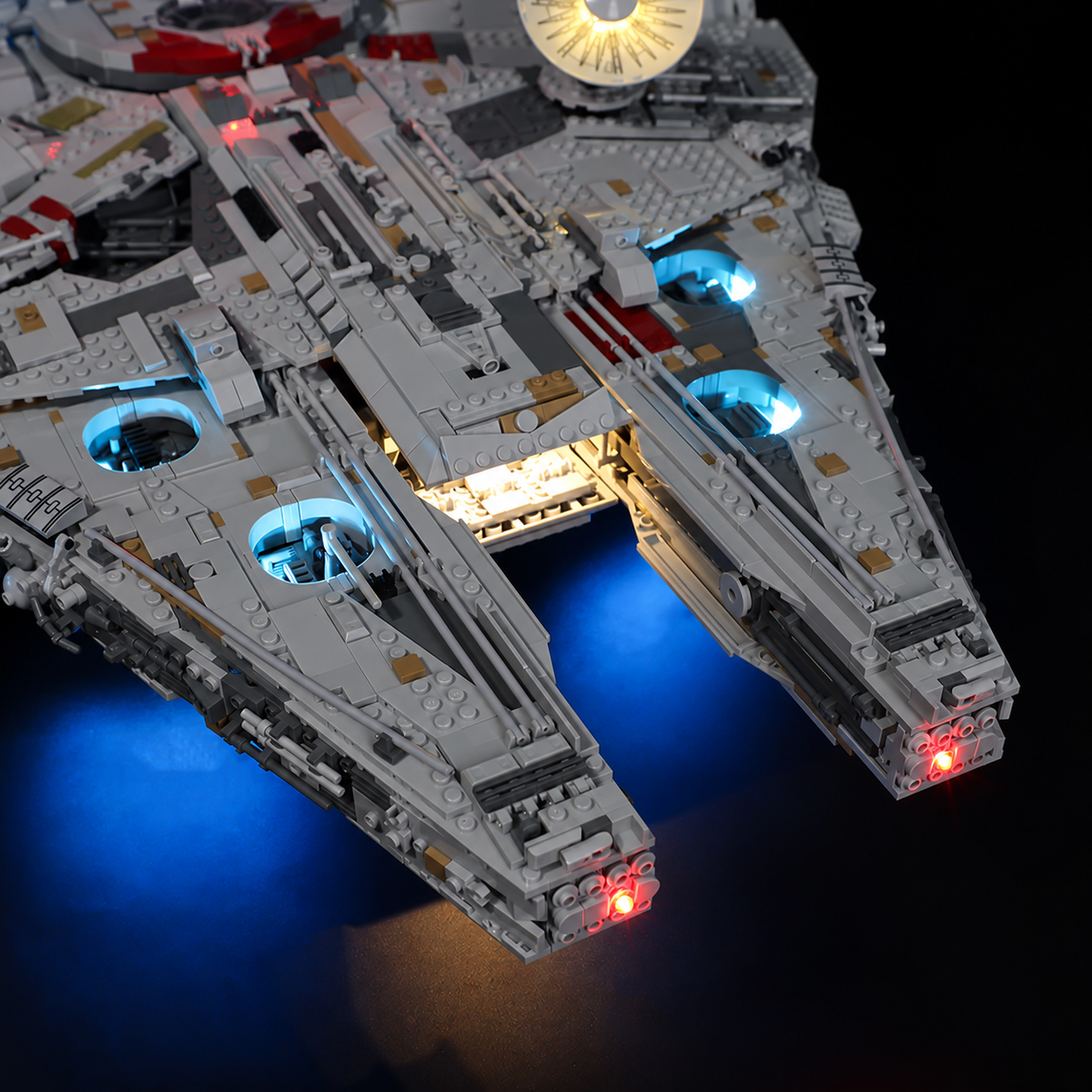 Close-up of the Millennium Falcon 75192 front mandibles with red tip lights, blue accent lights and a warm-lit central opening.