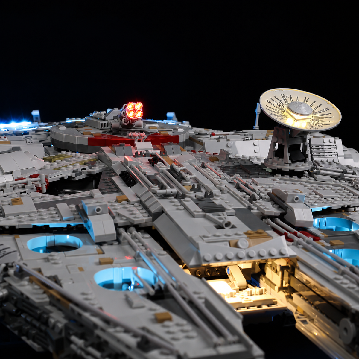 Upper hull of LEGO Millennium Falcon 75192 with a warm-lit radar dish, red cannon lights and blue accents.