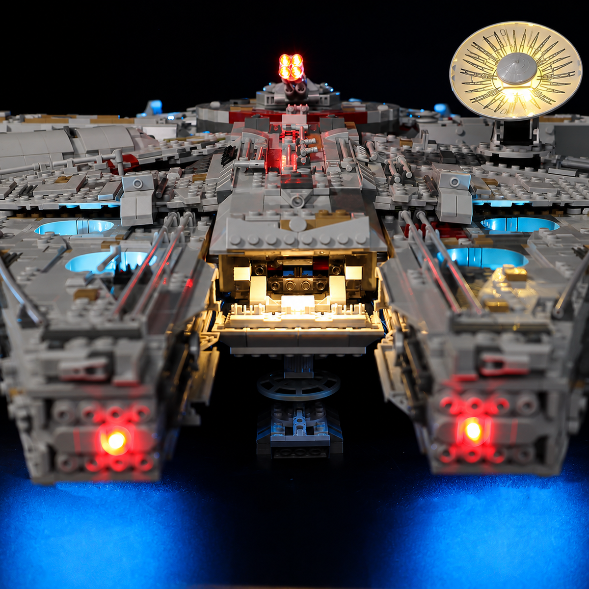 Front view of LEGO Millennium Falcon 75192 with red mandible lights, a warm-lit central opening and blue underglow.
