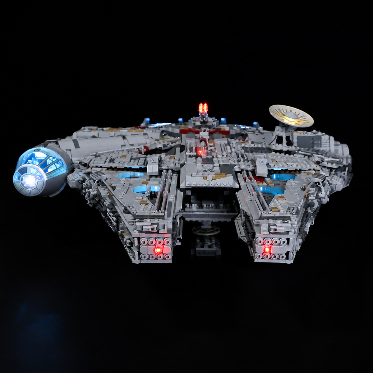 Low head-on view of LEGO Millennium Falcon 75192 showing its illuminated cockpit, red front lights and blue underglow.