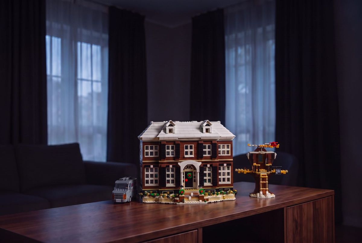 The lit McCallister house displayed on a walnut sideboard in an evening room — lifestyle visualisation