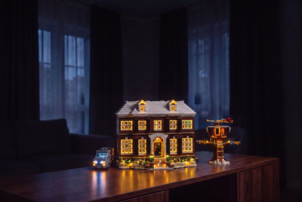 The lit McCallister house displayed on a walnut sideboard in an evening room — lifestyle visualisation