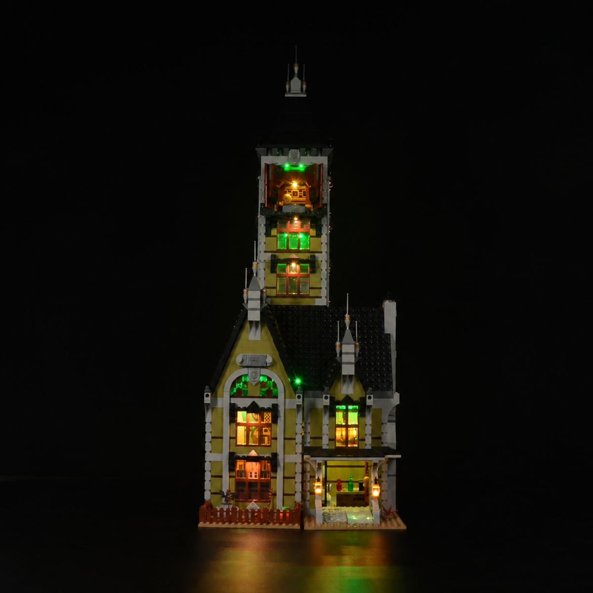LEGO® Haunted House 10273 entrance with two warm lanterns and illuminated windows, lit by Game of Bricks Lights.