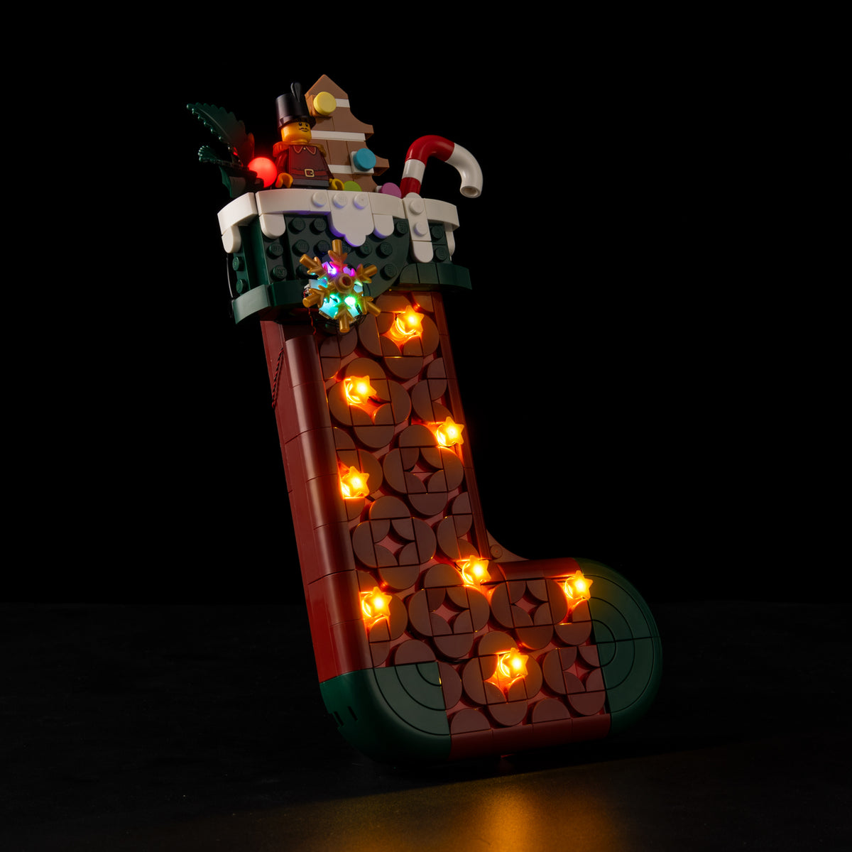 Real side-angle Shopify photograph showing the illuminated red stocking and green toe of LEGO® 40958.
