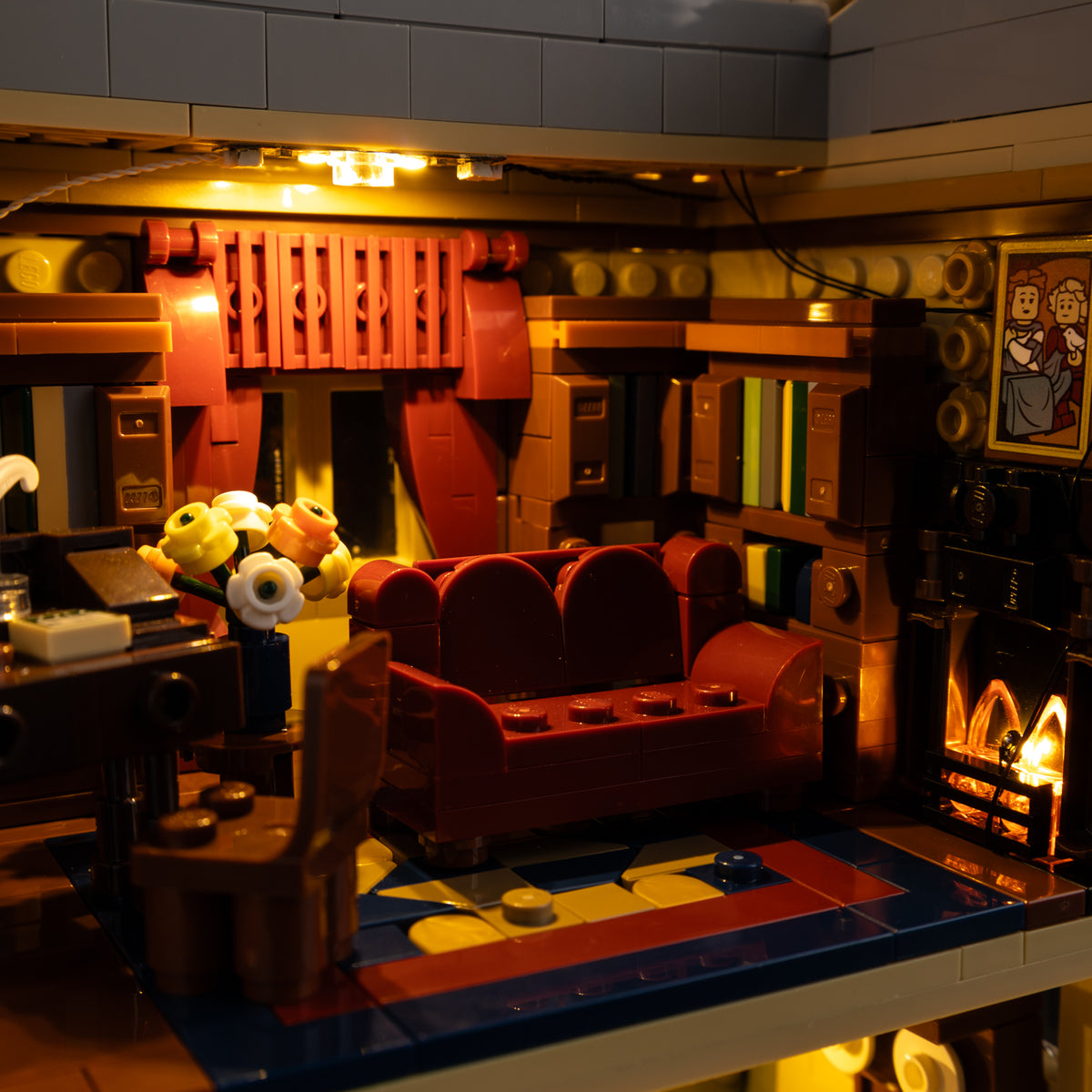 Downton Abbey library with red seating, bookshelves and glowing fireplace